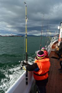 Passengers wearing life jackets and holding fishing rods on a sea angling boat tour in Reykjavík, Iceland.