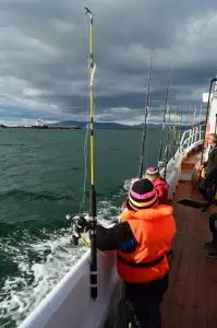 Passengers wearing life jackets and holding fishing rods on a sea angling boat tour in Reykjavík, Iceland.