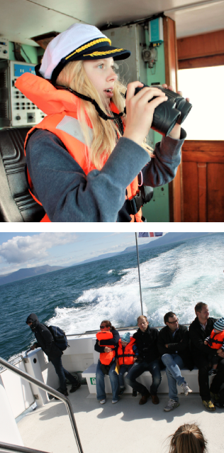 Young woman with a captain's hat and life jacket looking through binoculars, with a group of people on a boat deck in the lower section.